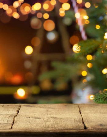 Empty wooden table on Christmas ornaments background with fireplace.